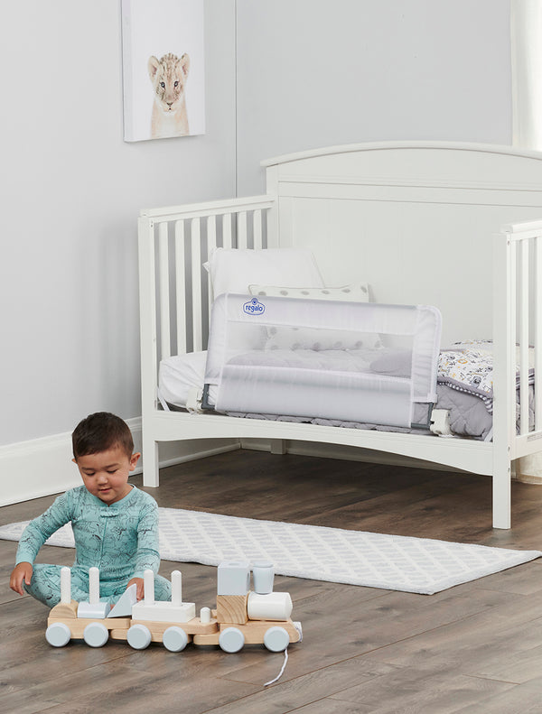 Child plays in front of Swing Down Convertible Crib Rail