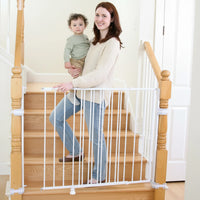 Mom holding toddler walking down stairs opening the safety gate