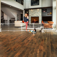 Mom holding baby walking through door of the baby gate. 