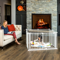 Mom reading on couch watching toddler play in play yard.