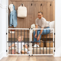 Mom tying shoe while baby play on the floor behind wooden safety gate