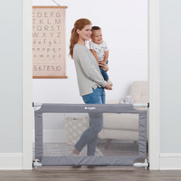 Mom holing toddler behind gate