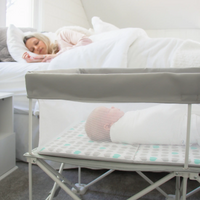 Mom sleeping in bed while baby sleeps in My Crib next to her