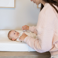 Baby laying on Infant changing pad looking up at mom