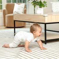 Baby crawling in front of coffee table with corner cushions