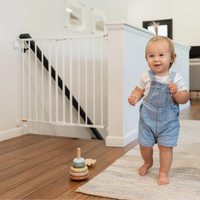 Toddler walking by top of stairs gate
