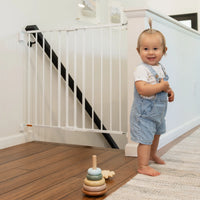 Toddler standing by top of stairs gate