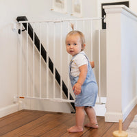 Toddler standing by top of stairs gate