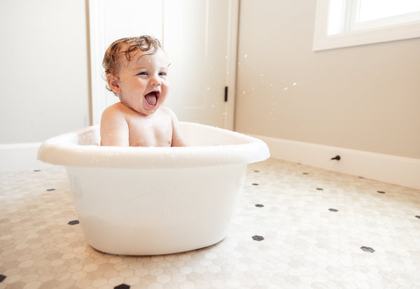 Happy baby laughing in the Baby Basics™ Grow with Me Baby Bath Tub