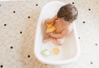Baby plays with toys in the Baby Basics™ Grow with Me Baby Bath Tub