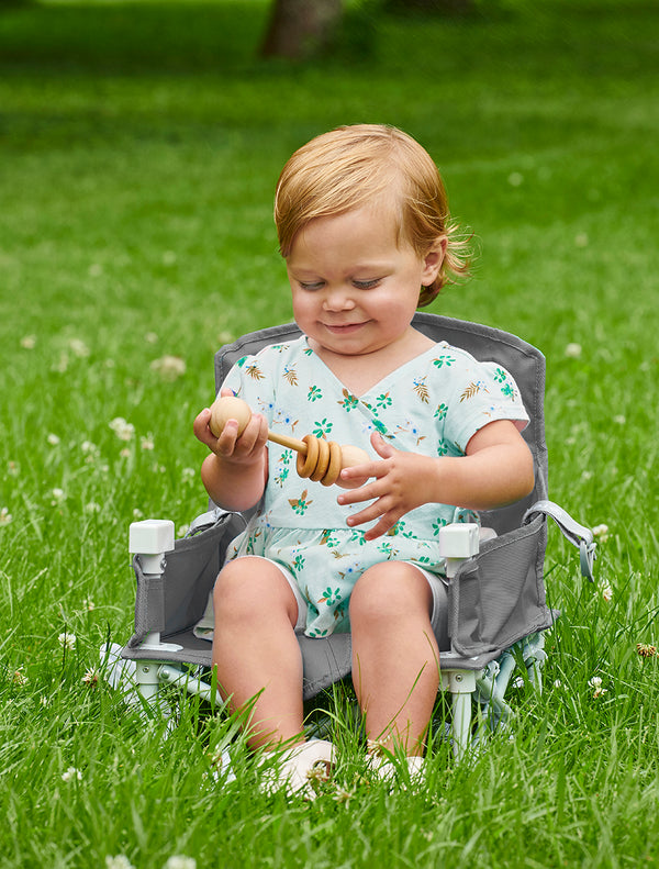 Child seated in the My Chair™ Portable Booster Seat in the grass
