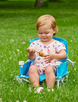 Child plays with toy in My Chair™ Portable Booster Seat in the grass outside