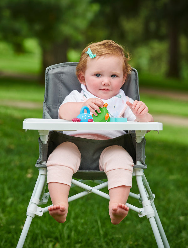 Child sits in My Portable High Chair™ with Tray - Gray