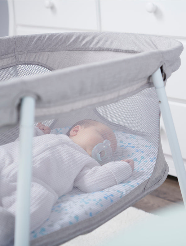 Baby sleeps in the Baby Basics™ Infant Bassinet side view