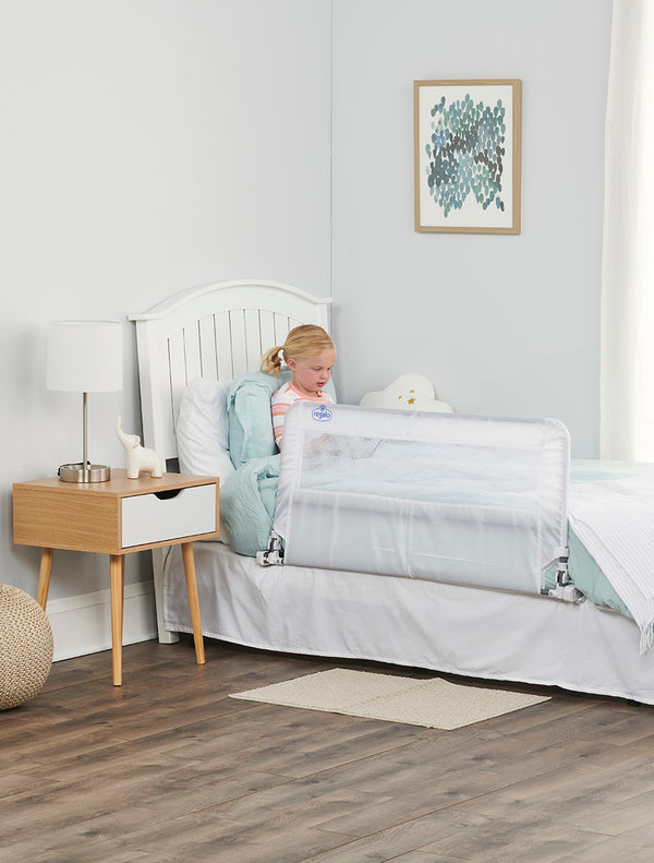Child sits on bed by the HideAway Bed Rail