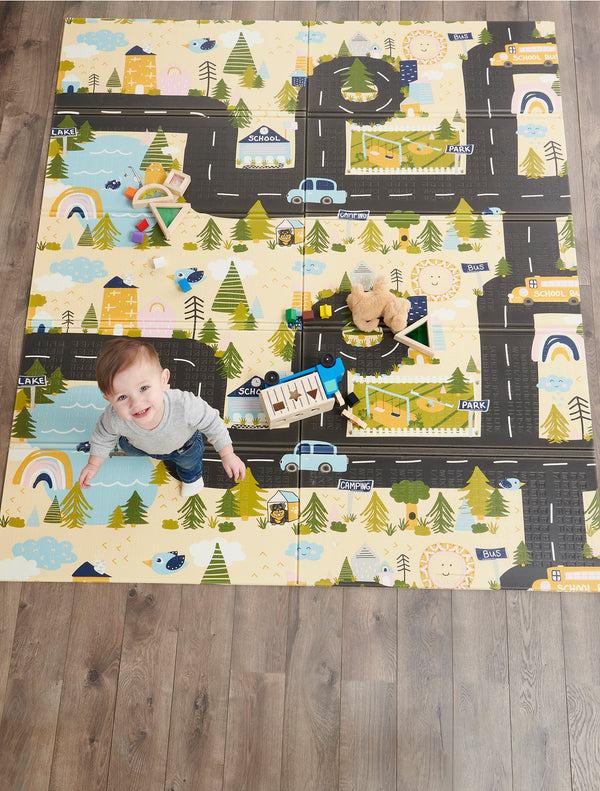 Child looks up from My Around Town Play Mat®