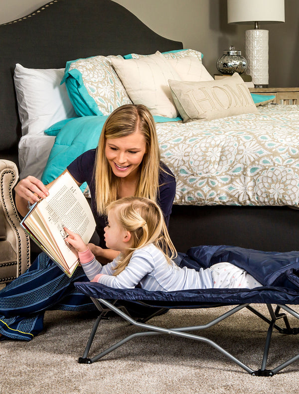 Child looks at book while on the Deluxe My Cot® Portable Toddler Travel Bed™