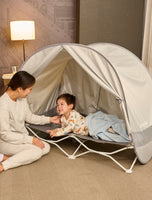 Child laying on My Cot® with Canopy Portable Toddler Bed™