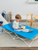 Child sits up looking at book on My Cot® Pals Portable Toddler Bed - Blue Raccoon