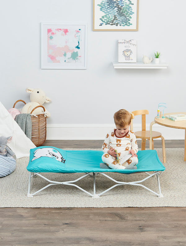 Child sitting up looking at a book on the My Cot® Pals Portable Toddler Bed - Teal Bear