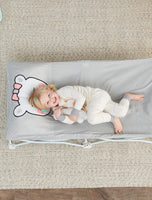 Child looks up from Gray Polar Bear My Cot Pals Portable Toddler Bed