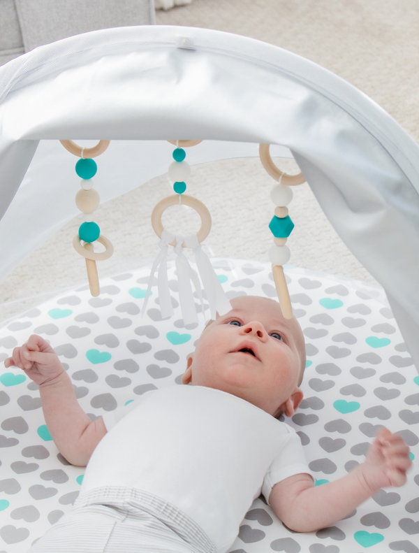 Baby looks up at toys on the Baby Basics™ Foldable Infant Play Mat