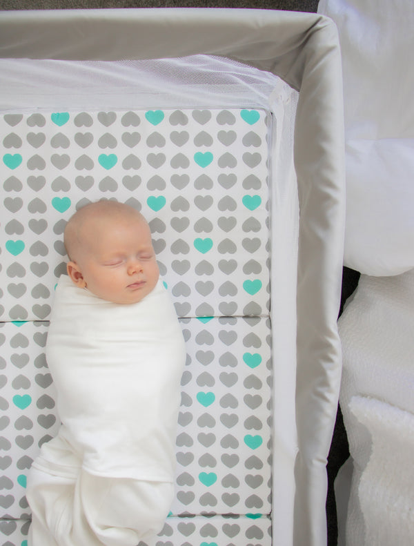 Baby wrapped up and sleeping in My Crib® Portable Bassinet