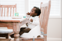 Baby eating in Baby Basics™ Booster Seat 